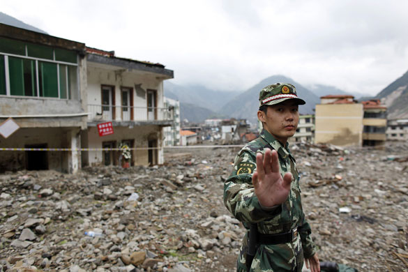 1 April 2009: Beichuan, China: A soldier stands amongst rubble