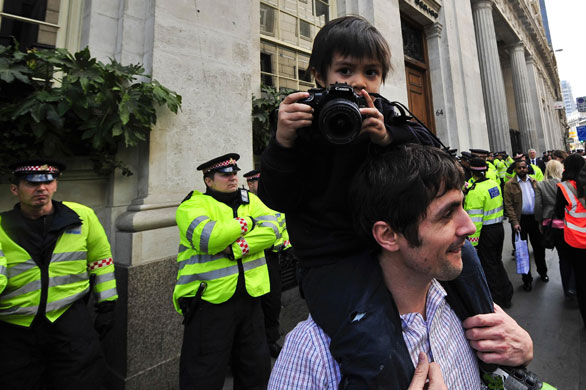 The Media at G20: A young photographer take photos on a man's shoulders of the G20 protesters
