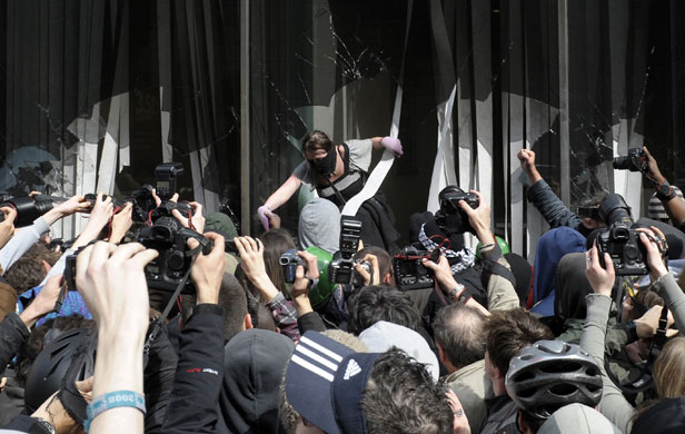 The Media at G20: A demonstrator climbs out of broken windows 