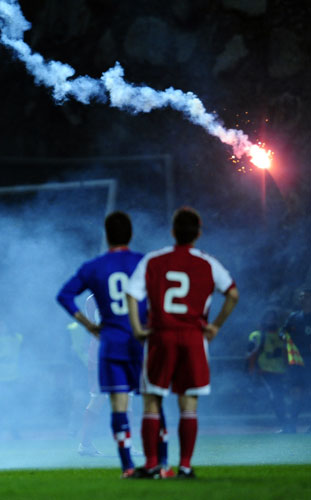 World Cup 2010 Qualifiers: Players watch as fans throw flares onto the pitch 