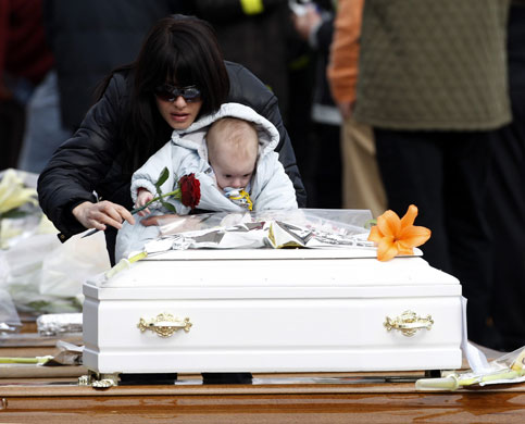 Italy earthquake funerals: Woman and her son leave a rose during the state funeral ceremony.