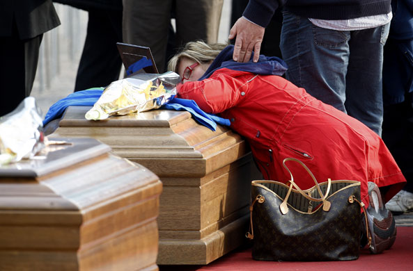 Italy earthquake funerals: A woman kneels over a coffin prior to the funerals for earthquake victims.