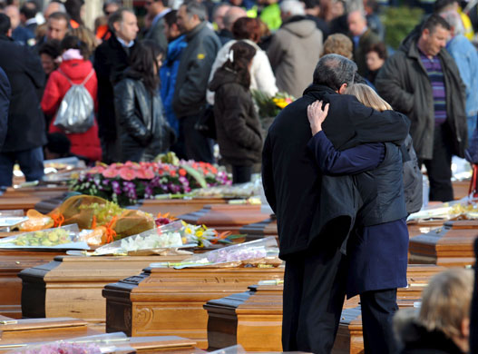 Italy earthquake funerals: People mourn as they stand between dozens of wooden coffins.