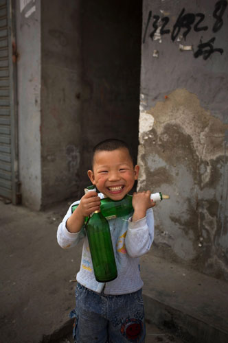 24 hours in pictures: Dawangjing, China:  A boy plays with beer bottles