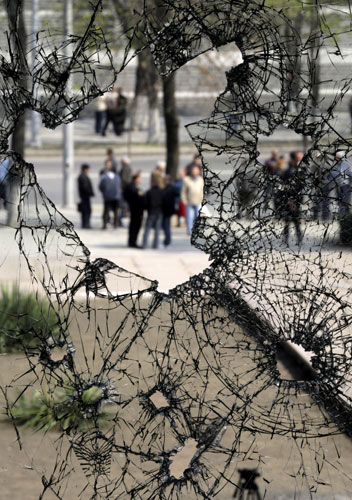 24 hours in pictures: Chisinau, Moldova: People seen through the broken windows of parliament.