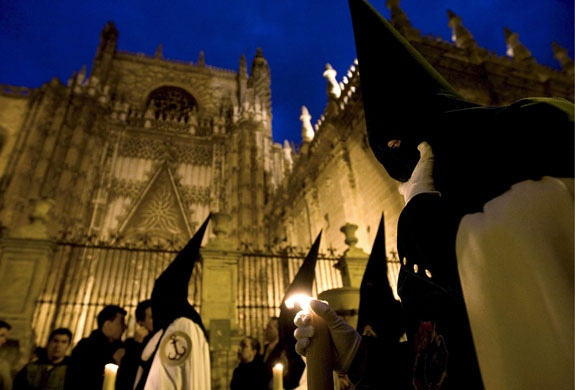 24 hours in pictures: Seville, Spain: Penitents of the Esperanza de Triana  brotherhood.