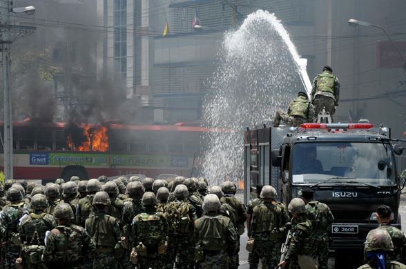 Thailand protests: Thai soldiers use a water canon to douse flames coming from a bus.