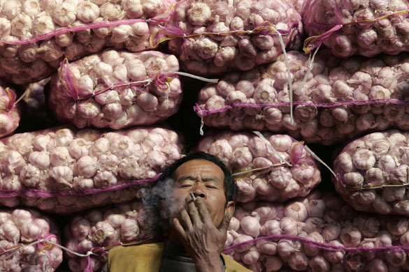 24 hours in pictures: A vendor smokes as he sells garlic at a wholesale market in Taiyuan
