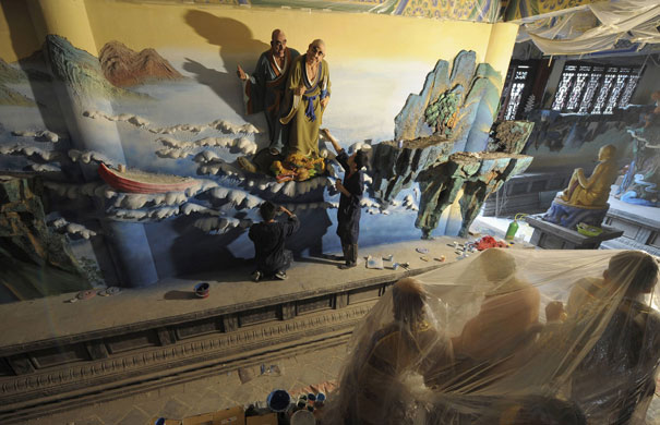 24 hours in pictures: Chongqing, China:  Workers paint a sculpture of saints.