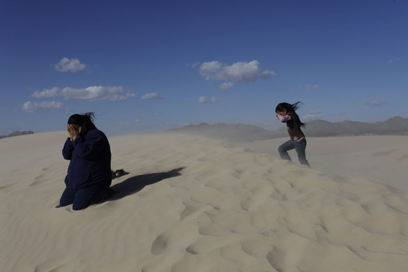 24 hours in pictures: Samalayuca, Mexico: A mother and her daughter cover their faces from sand.