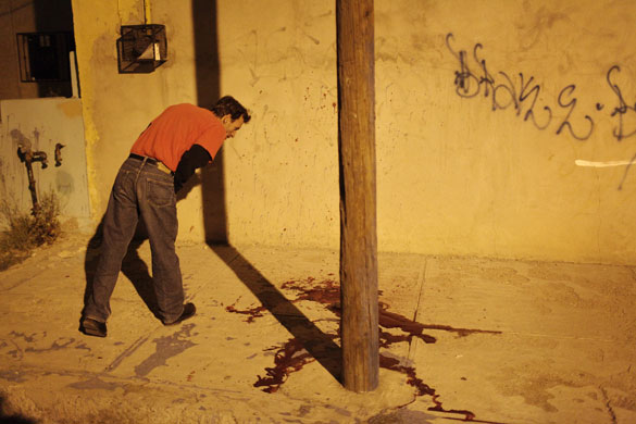14 April 2009: Ciudad Juarez, Mexico: A resident looks at a pool of blood