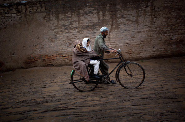 24 hours in pictures: Pakistani man pushes his bicycle carrying his daughters