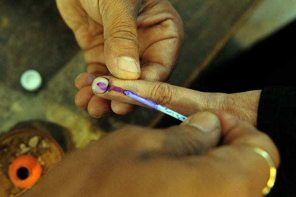 Elections in India: An election officer marks the finger of a voter with ink in Varanasi