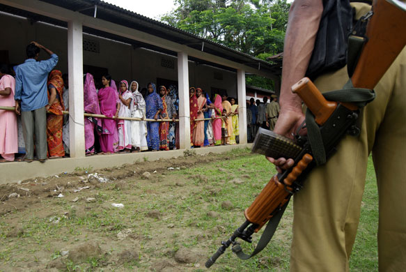 Elections in India: A security official stands guard as voters queue in Jatingamukh