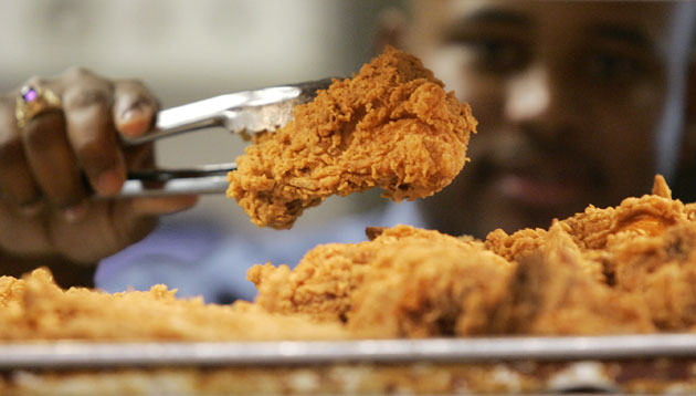 Week in business: A Kentucky Fried Chicken employee holds up a piece of fried chicken.  