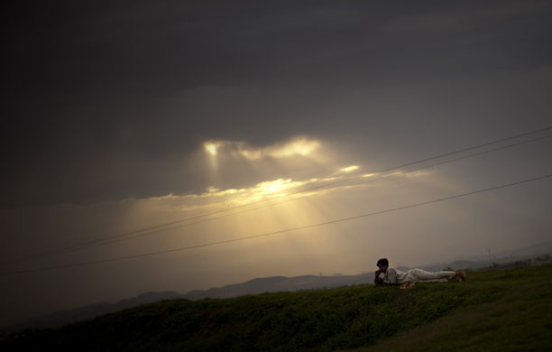 24 hours in pictures : A boy rests on the ground on the outskirts of  Islamabad, Pakistan