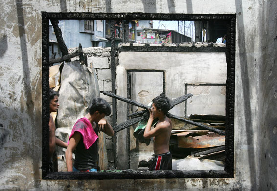 24 hours in pictures: Manila, Philippines: Local residents are framed in a burnt window frame.