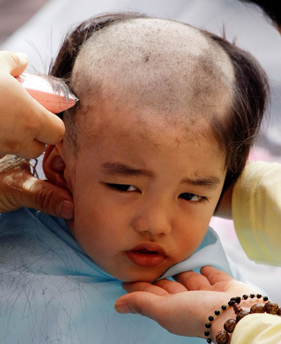 24 hours in pictures: Seoul, South Korea: A boy has his head shaved by a monk.