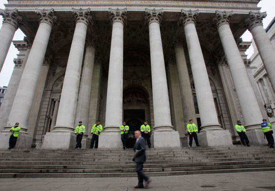 G20 protests day two: Police officers watch an office worker passes the Bank of England building