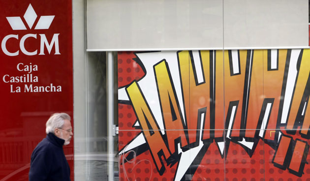 Week in Business: A man walks past a branch of Caja Castilla La Mancha in Madrid.