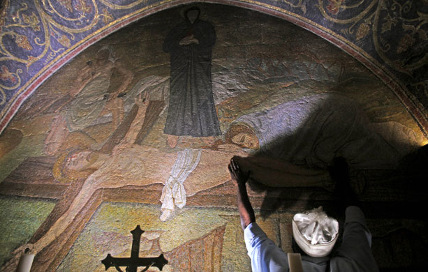24 hours in pictures: Christian pilgrim touches a mural depicting Jesus