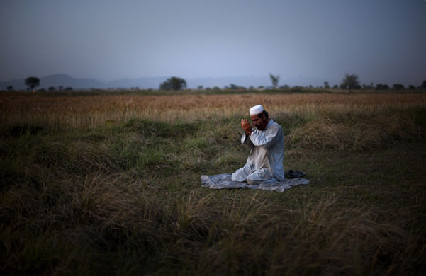 24 hours in pictures: Pakistani farm labourer prays after a day of work in a field