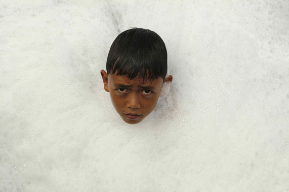 24 hours in pictures : A boy swims in polluted waters  at Pluit dam in Jakarta