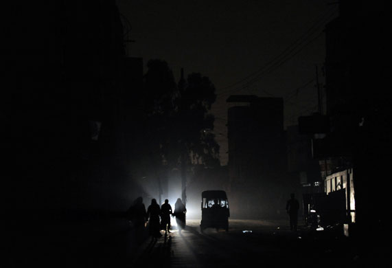 24 hours in pictures: Karachi, Pakistan: Residents walk on a street during a power cut 