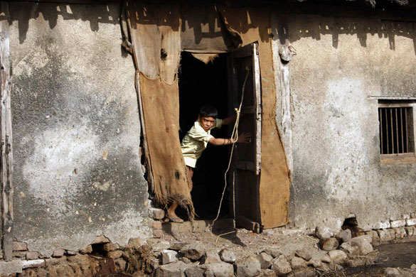 24 hours in pictures: A boy peeps out of his house in a village near Karjat