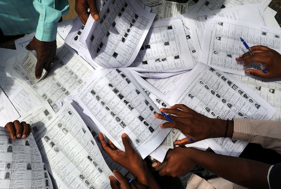 24 hours in pictures: Agents of a political party check the names and details of voter