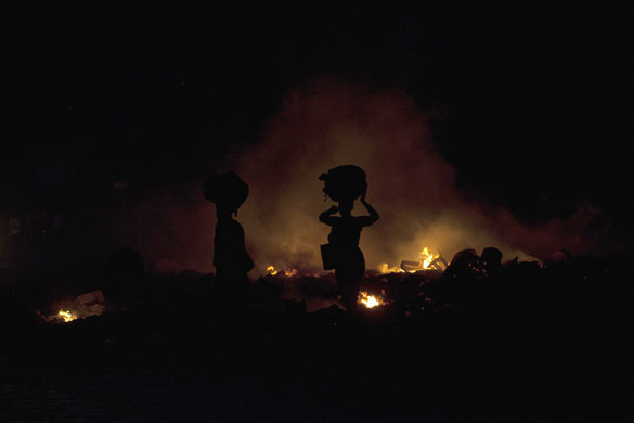 24 hours in pictures: Two women walk next to burning garbage in Port-au-Prince, Haiti