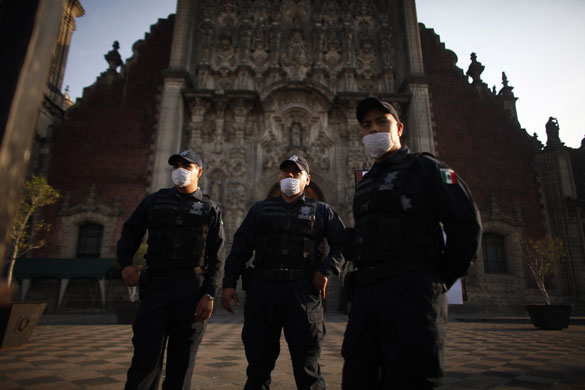 Swine flu : Police officers wearing masks outside a  cathedral  in Mexico City