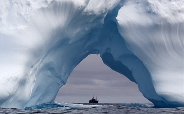 The Steve Irwin as seen through the arch of an iceberg as it sails through the Southern Ocean 