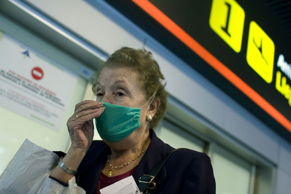 International Swine Flu: A passenger wearing a mask arrives at the Barajas Airport in Madrid