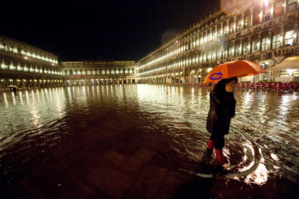 28 April 2009: Venice, Italy: A woman walks on the flooded Piazza San Marco