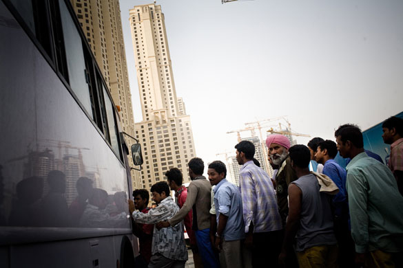 6 April 2009: Dubai, United Arab Emirates: Migrant workers line up for a bus