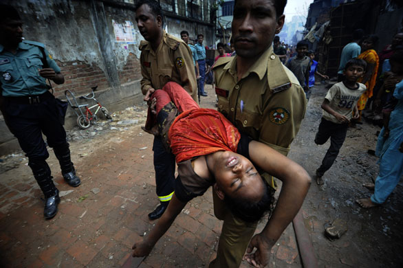 6 April 2009: Dhaka, Bangladesh: Firefighters rescue an injured woman from a slum