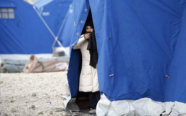 24 hours in pictures: A child peers from a tent at a camp in the village of Paganica