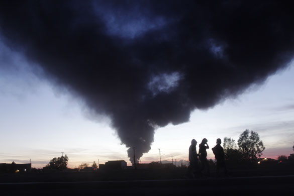 8 April 2009: Ciudad Juarez: Residents walk past the burning Foxcom manufacturing plant