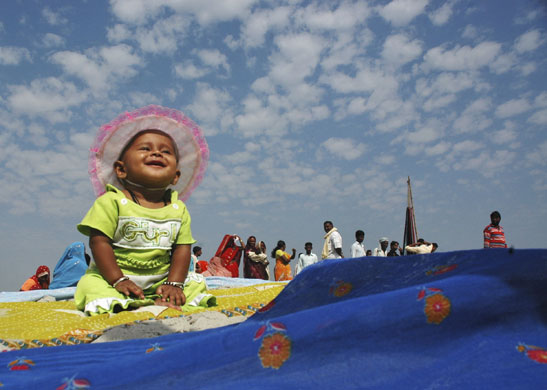 24 hours in pictures: A child sits washed clothes on banks of River Ganges