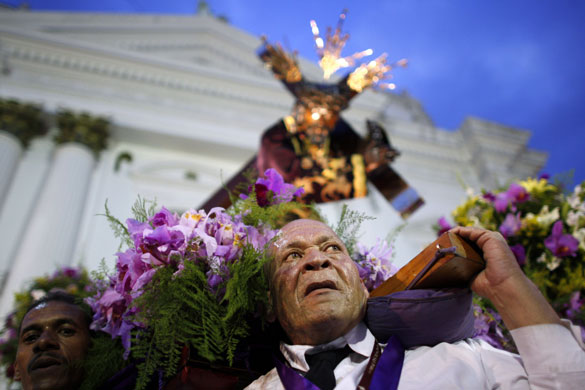 24 hours in pictures: A penitent carries a crucifix outside Santa Teresa's Basilica  in Caracas