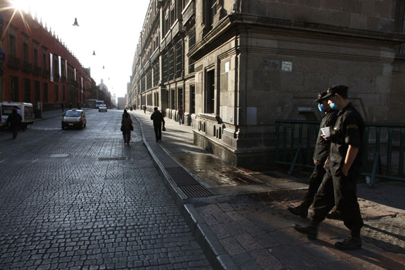 Mexico swine flu: Police officers wearing face masks patrol in the Zocalo Plaza.