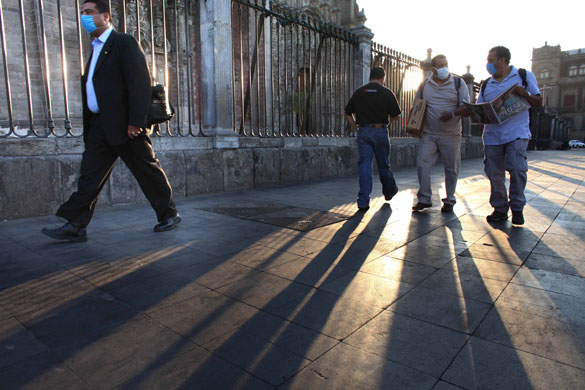 Mexico swine flu: Men wear surgical masks while walking past the Metropolitan Cathedral.