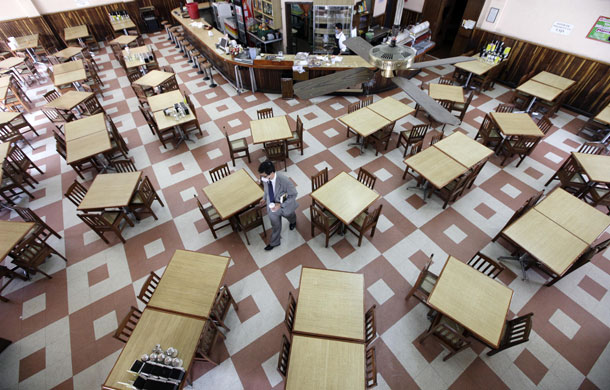 Mexico swine flu: A man carries his coffee past empty tables at the Cafe La Habana.