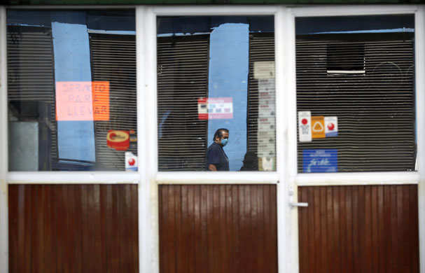 Mexico swine flu: A man wears a surgical mask reflected in a closed restaurant. 