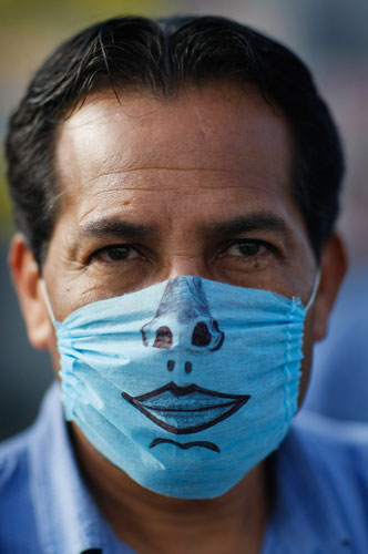 Swine flu face masks: A drawing-adorned surgical mask worn by a man in Mexico City