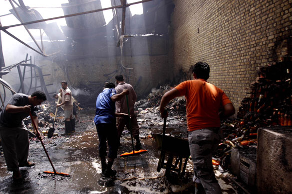 24 hours in pictures: Men clean up at a warehouse heavily damaged in a fire in Basra