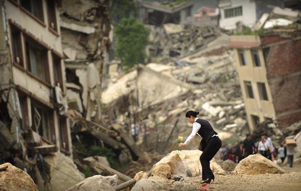 24 hours in pictures: woman places a flower in the town of Beichuan in China's earthquake