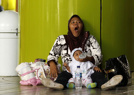 12 May 2009: Jakarta, Indonesia: A woman yawns as she feeds milk to her child
