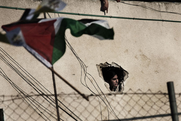 Pope Benedict XVI: A Palestinian woman peers from a hole at a house near a UN school